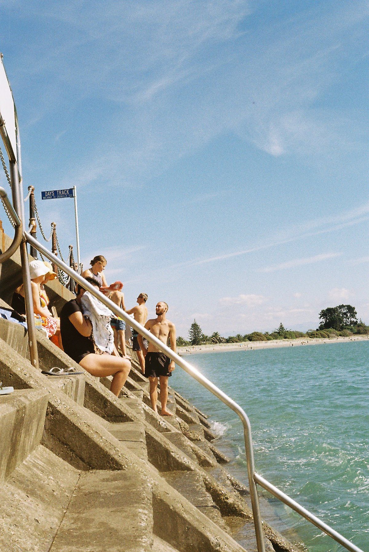 Friends jumping into the sea from concrete steps on a sunny day