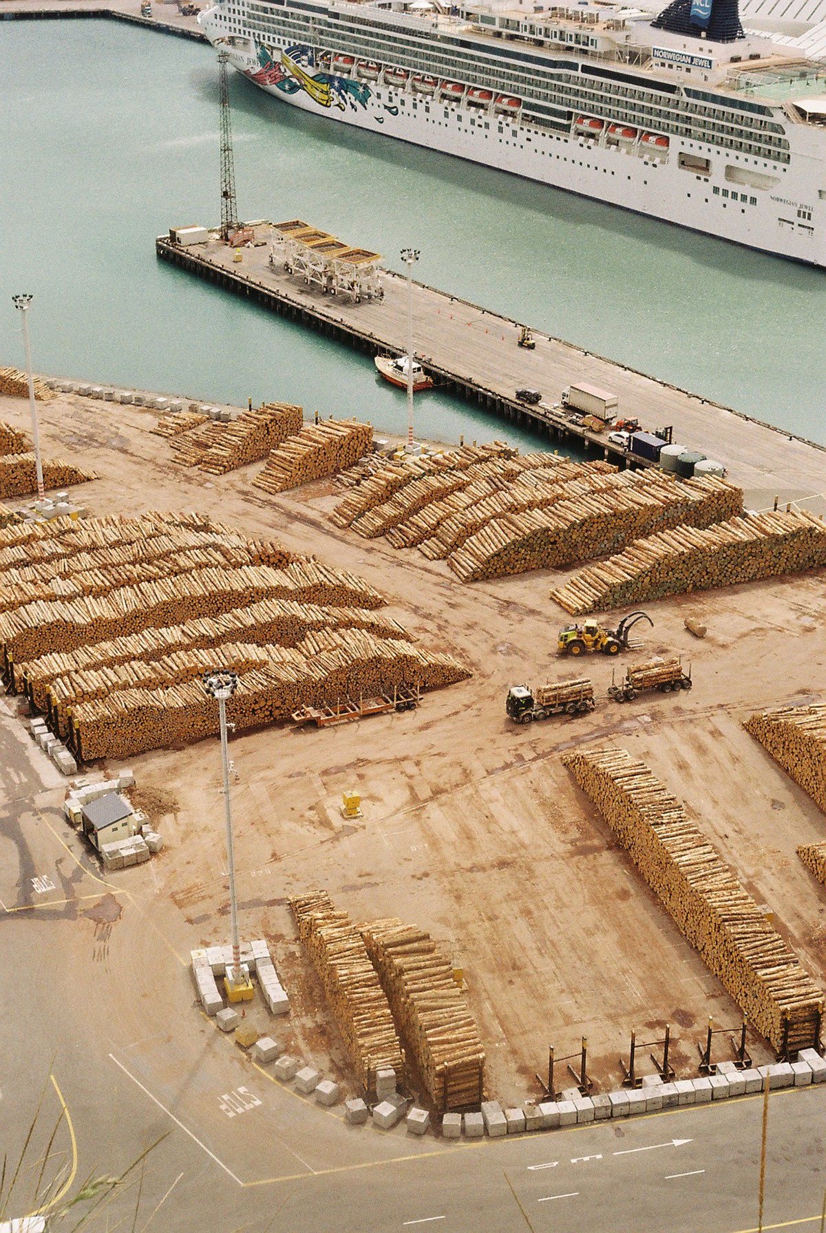 Aerial view of a log export yard beside a cruise ship in port