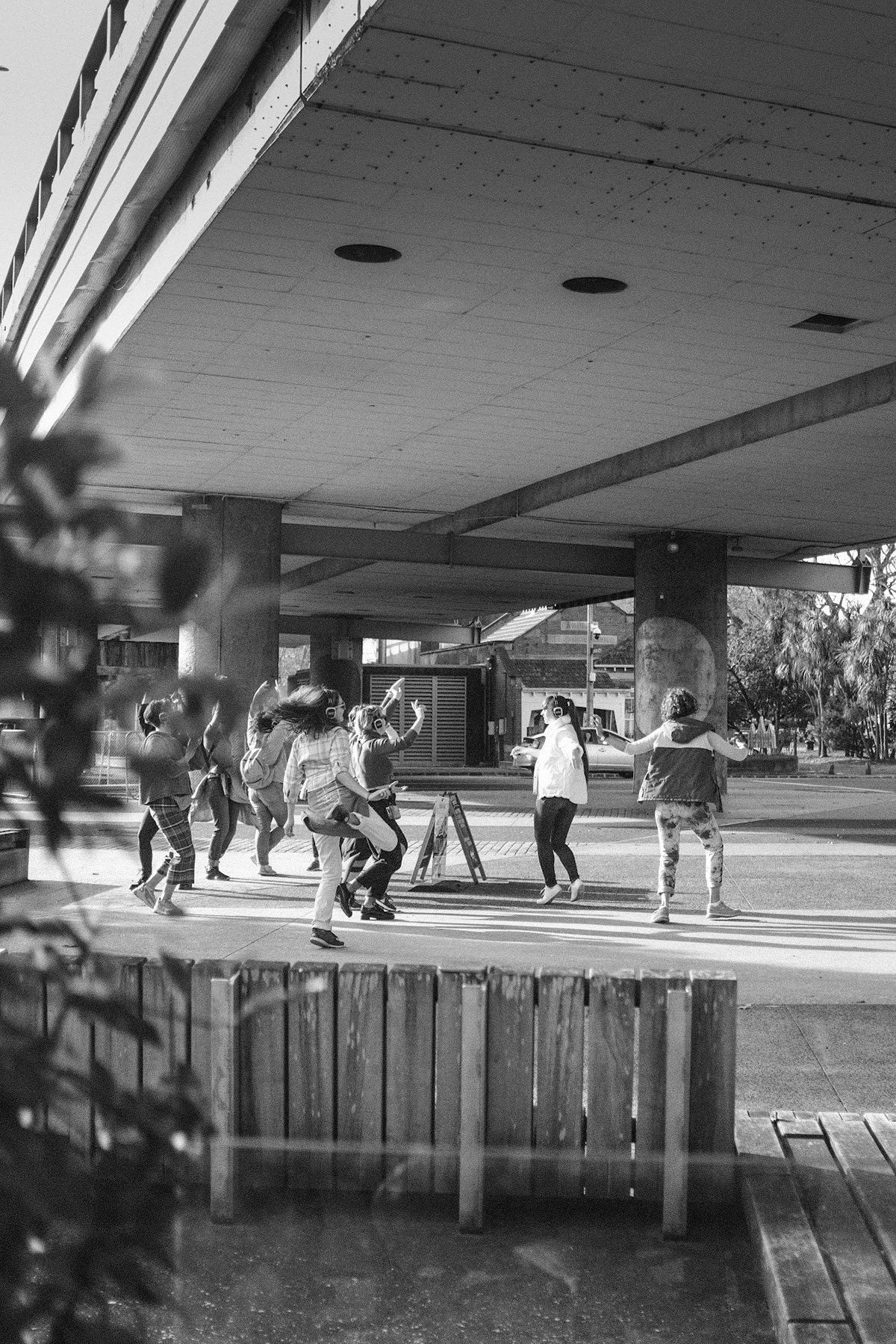 Black and white photo of dancers under a concrete overpass