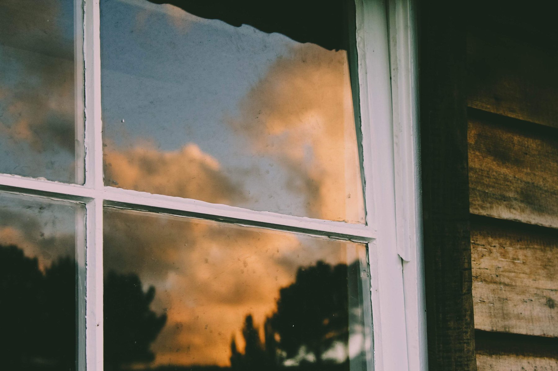 Sunset clouds reflected in an old timber-framed window